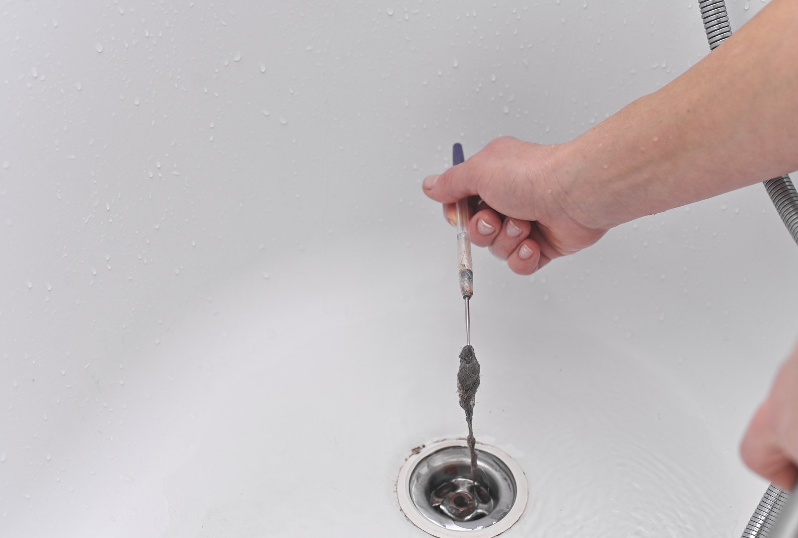 Illustrative close-up of hair being removed from a bath drain