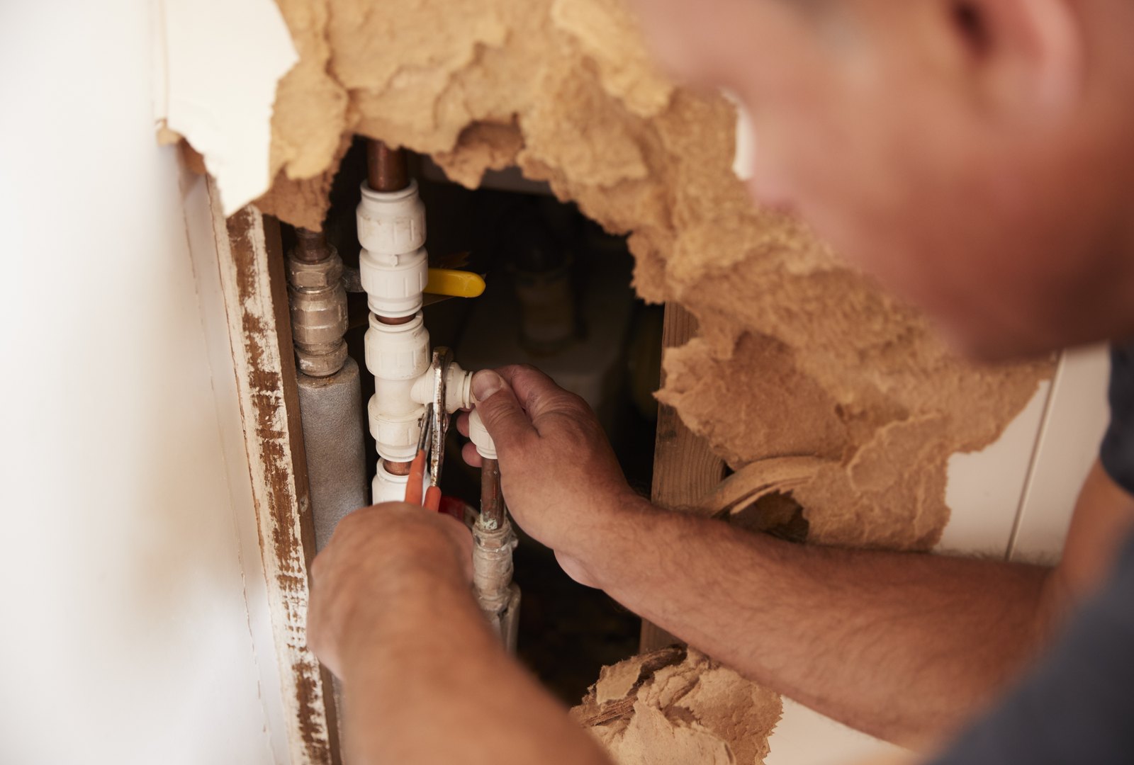 Illustrative close-up of hands repairing exposed household pipework